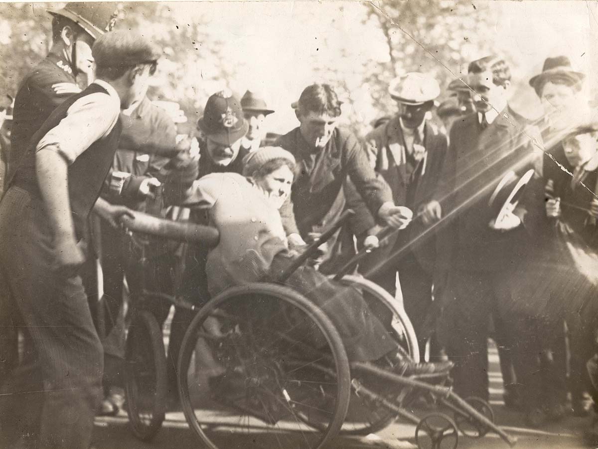 Group of men and boys, including some in police uniforms, surrounding woman in an adapted tricycle.