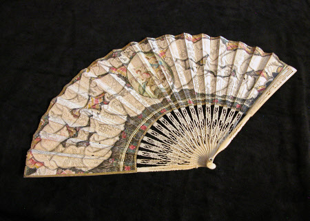 Cream coloured , decorated fan laid open on black background.