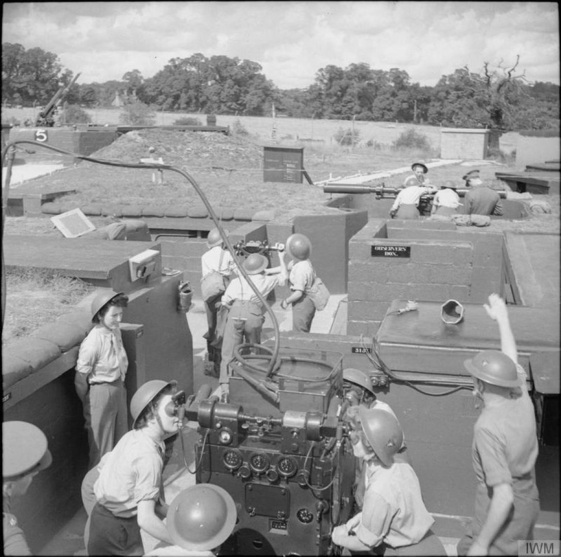 A group of women in metal protective hats operating the gun emplacement at Butt Farm. They are based in a trench type system and working as a team.