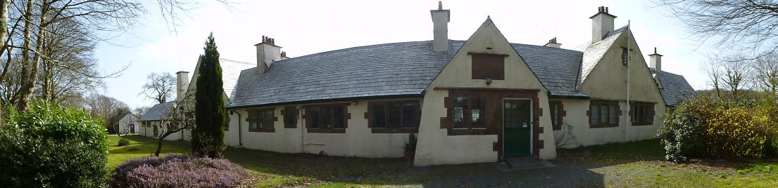 A panoramic picture of the outside of a white plastered cottage hospital.