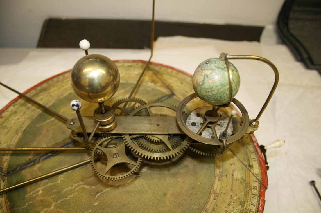 A Mechanical model showing a model of the earth that with gogs, will turn around a centre golden orb (sun) representing the earths rotation.