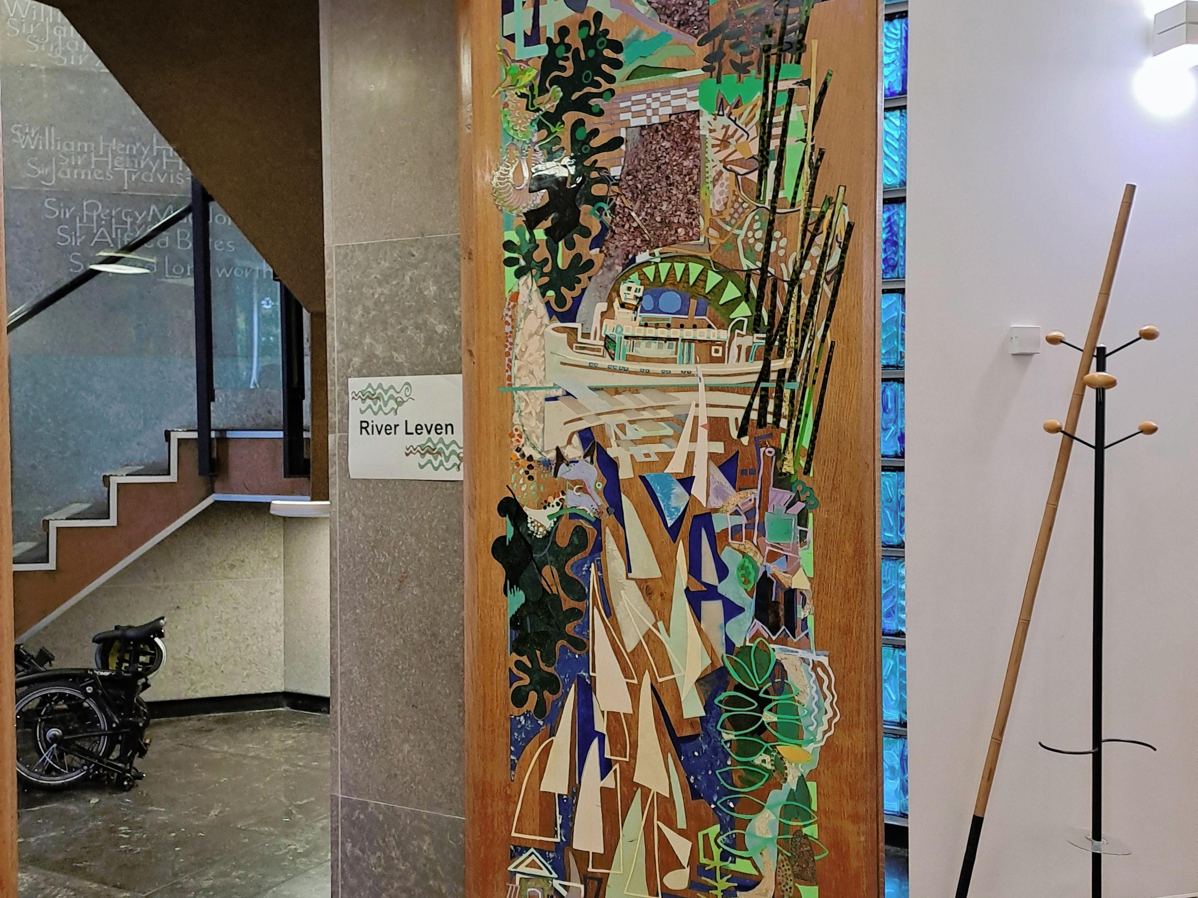 Colourful, semi-abstract artistic design of river scene on a modern wooden door in a building with white walls and grey floor.