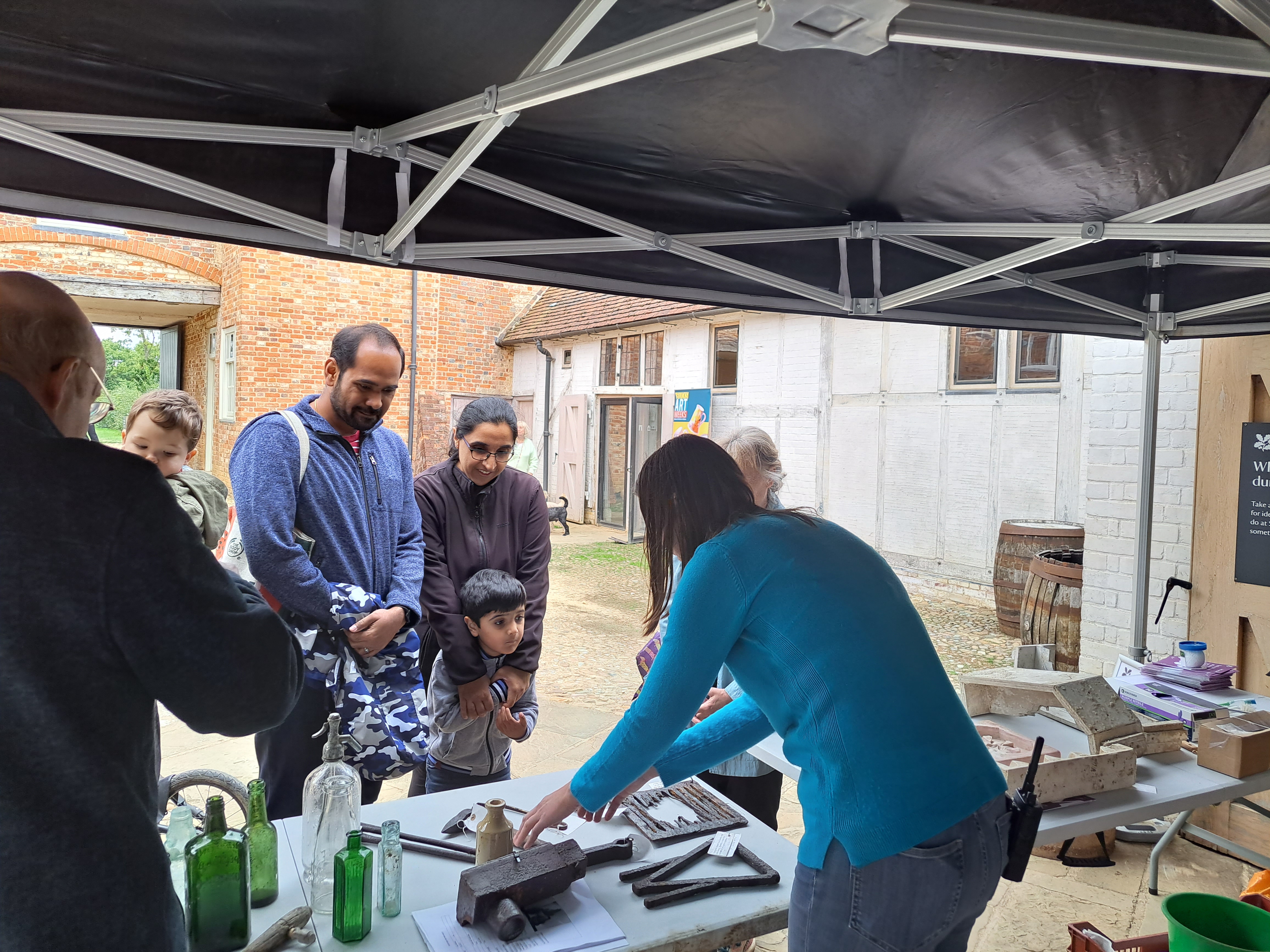 Woman at a stall in a courtyard engaging with a family.