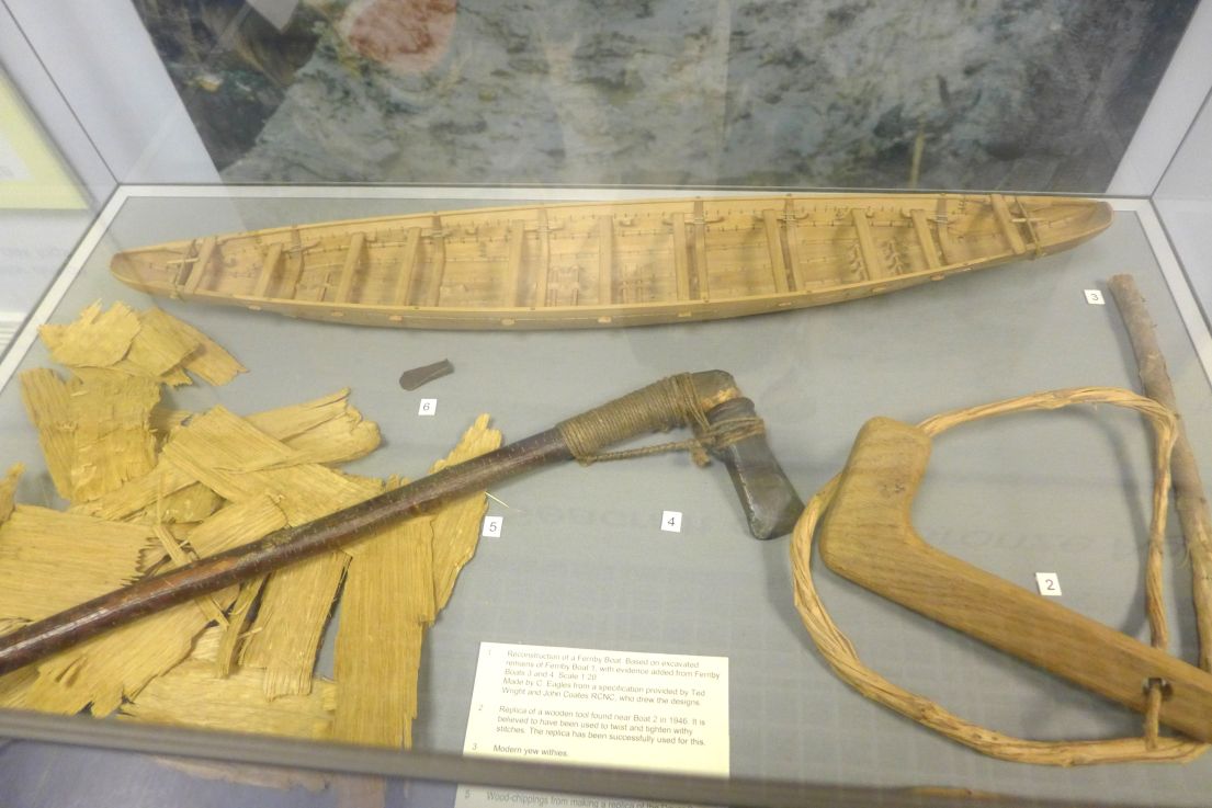 Museum display of a prehistoric boat with model and replica tools