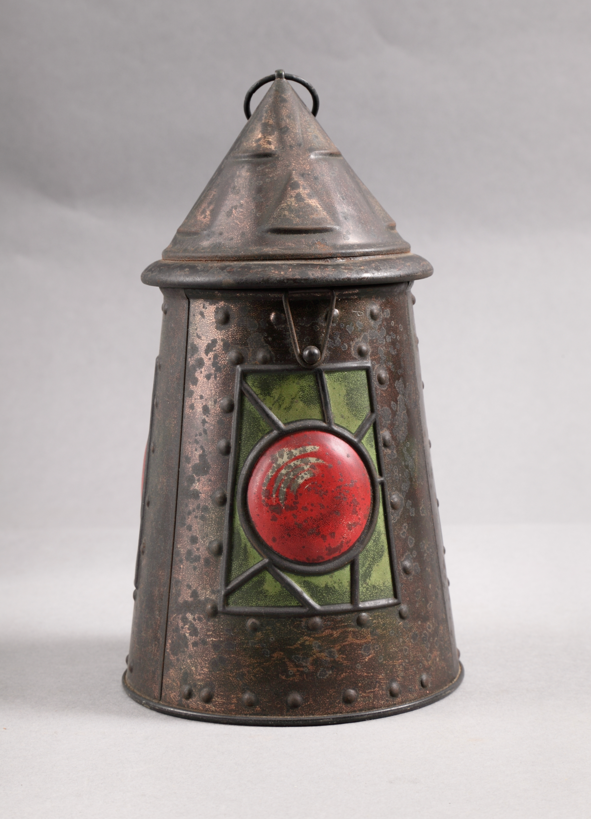 Metal tin in a lantern shape with a green and red pattern to mimic the light shining out.