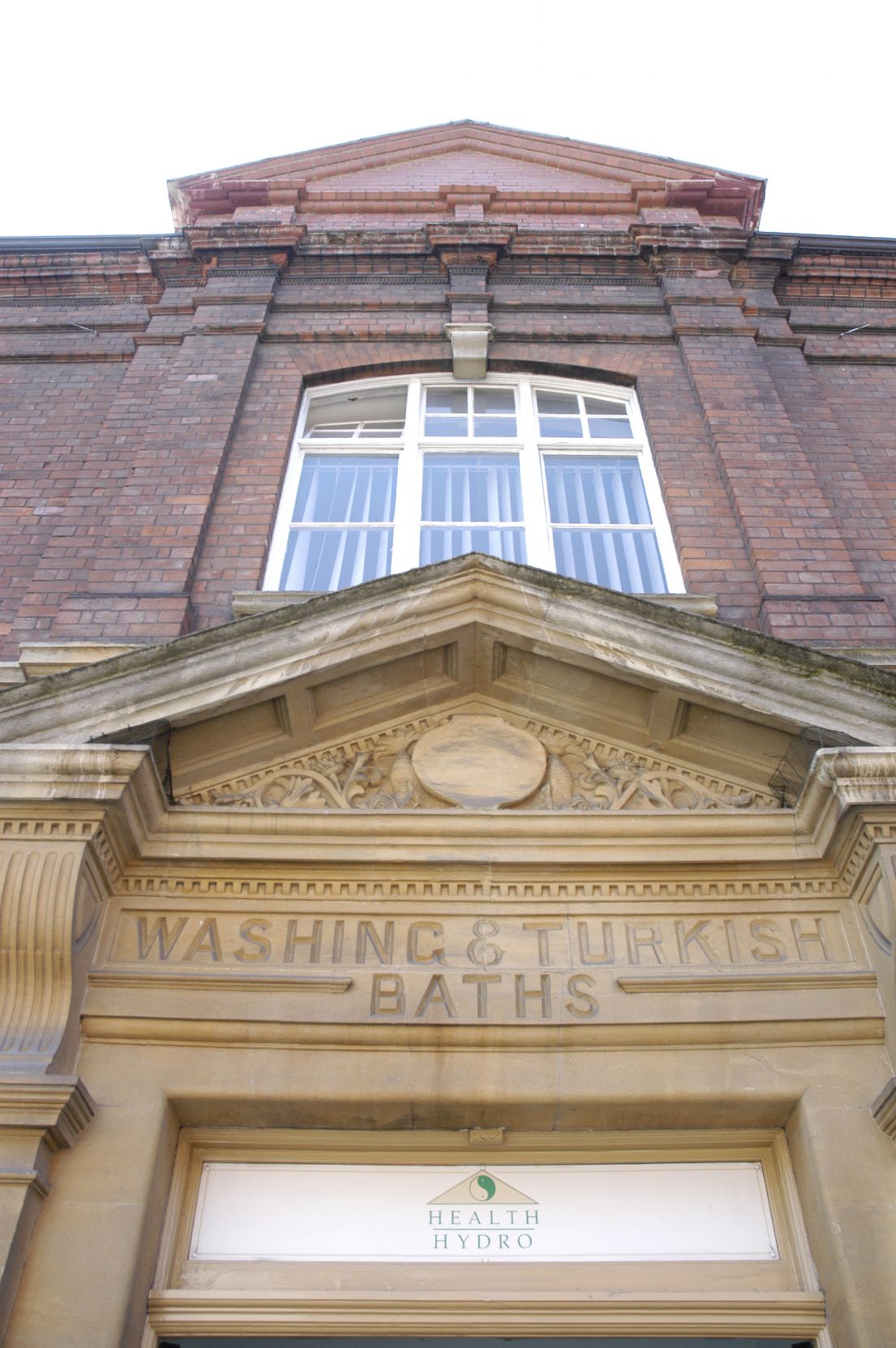 An stone archway to a brick building. engraved in the stone above the door reads 'Washing Turkish Baths'.