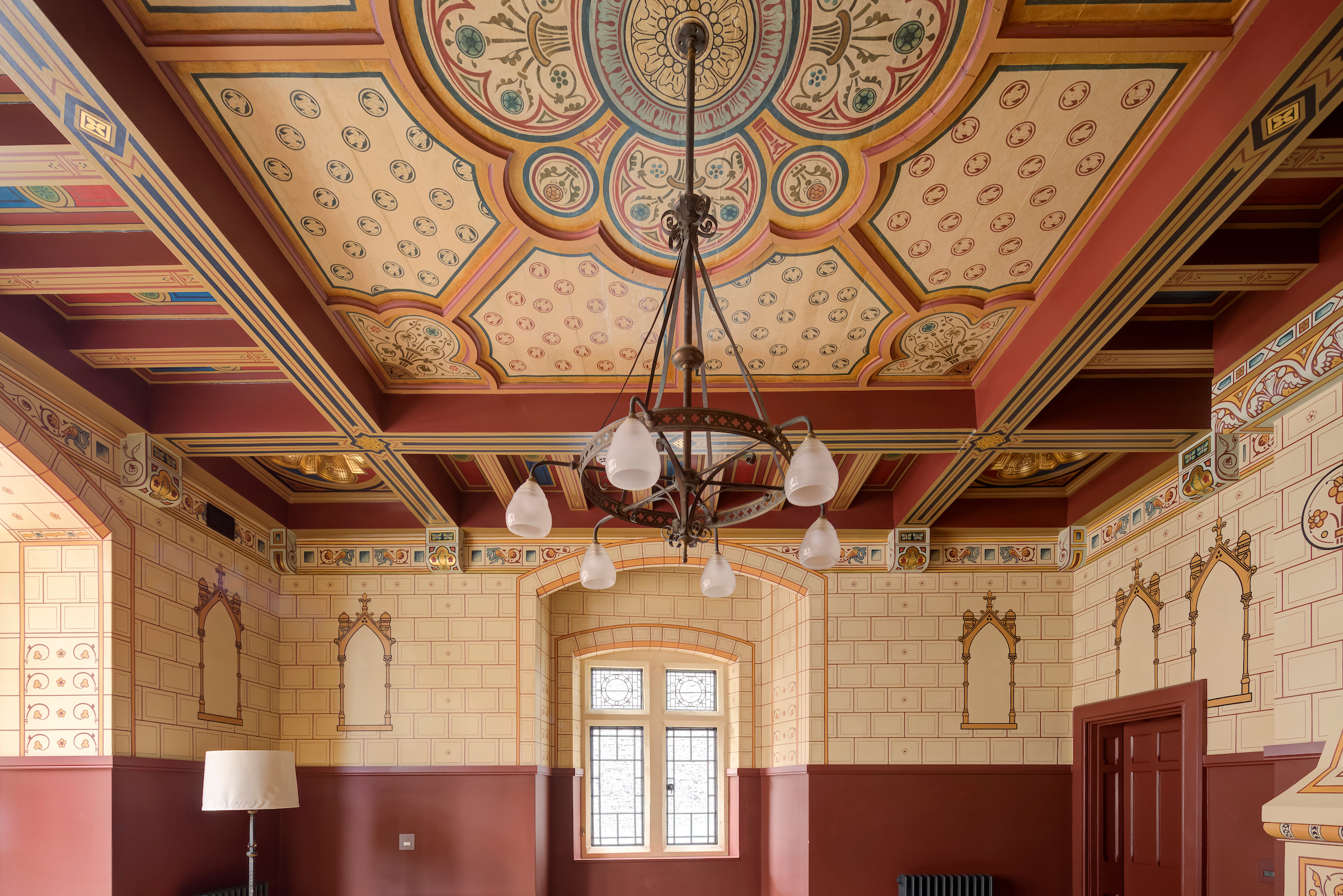 Room with walls and celing painted in red, cream and blue patterns.