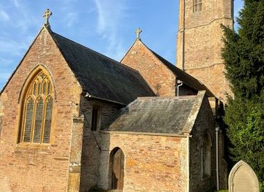 local photographer view of church from closed churchyard, stocks, ancient headstones and tombs