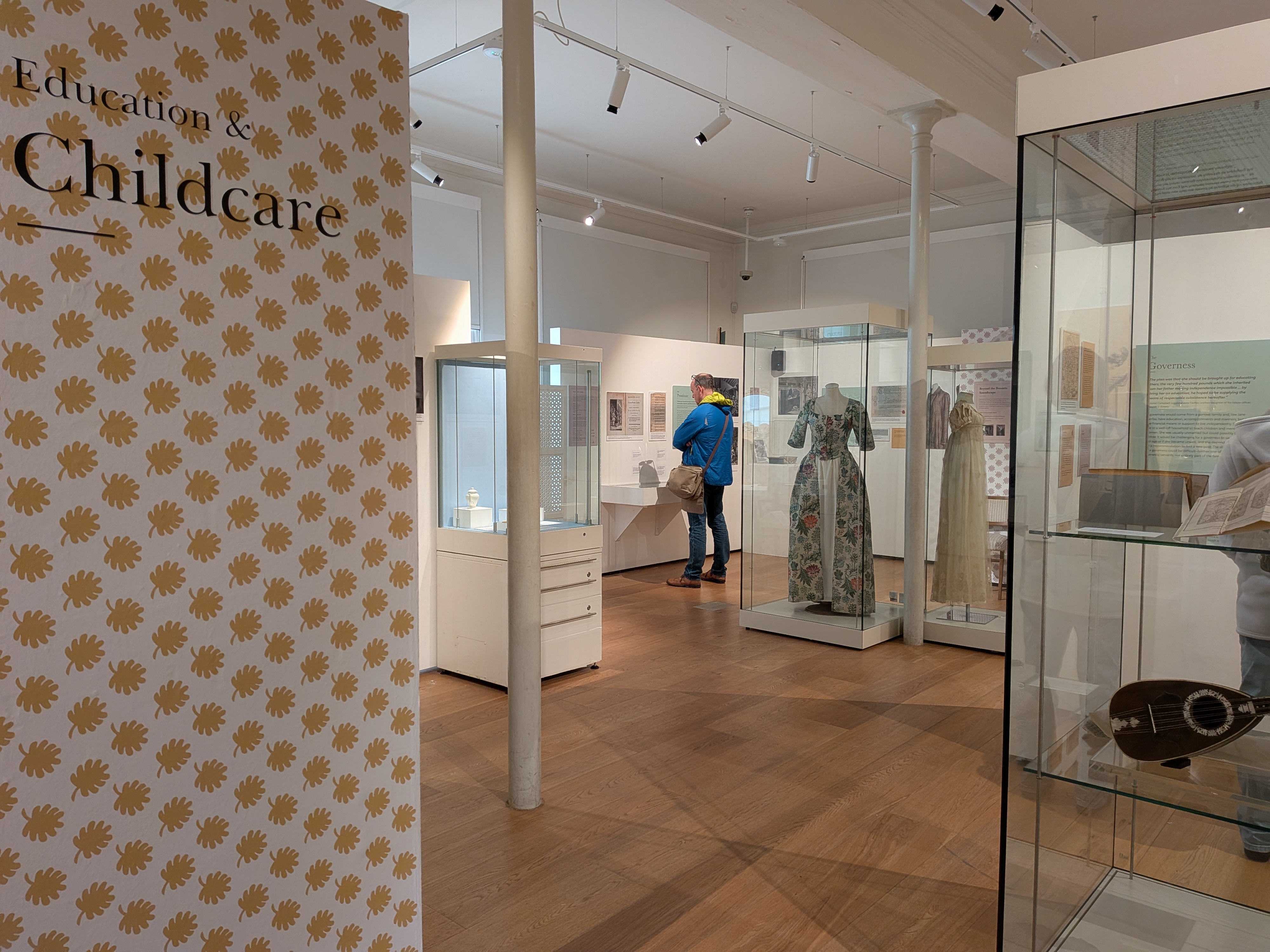 Exhibition room with glass cases holding dresses and musical instruments.
