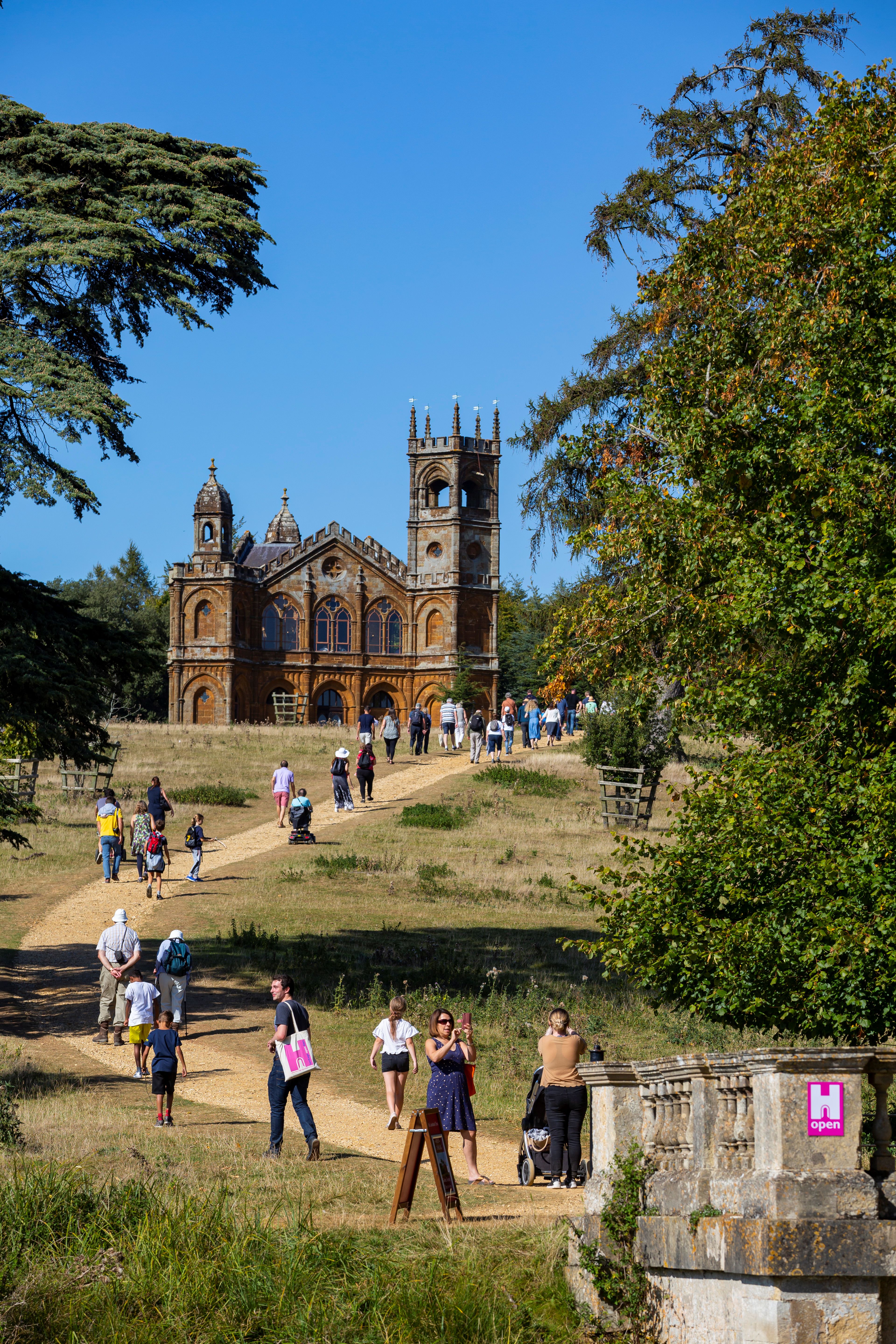 Lots of people walking up a curving path towards a Gothic building.
